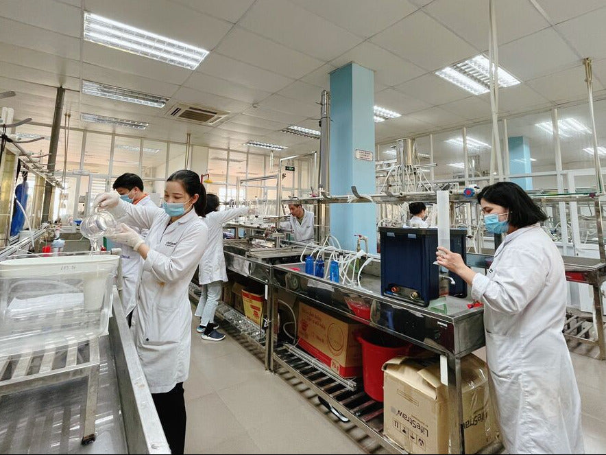 Laboratory setting with workers in white lab coats and masks.